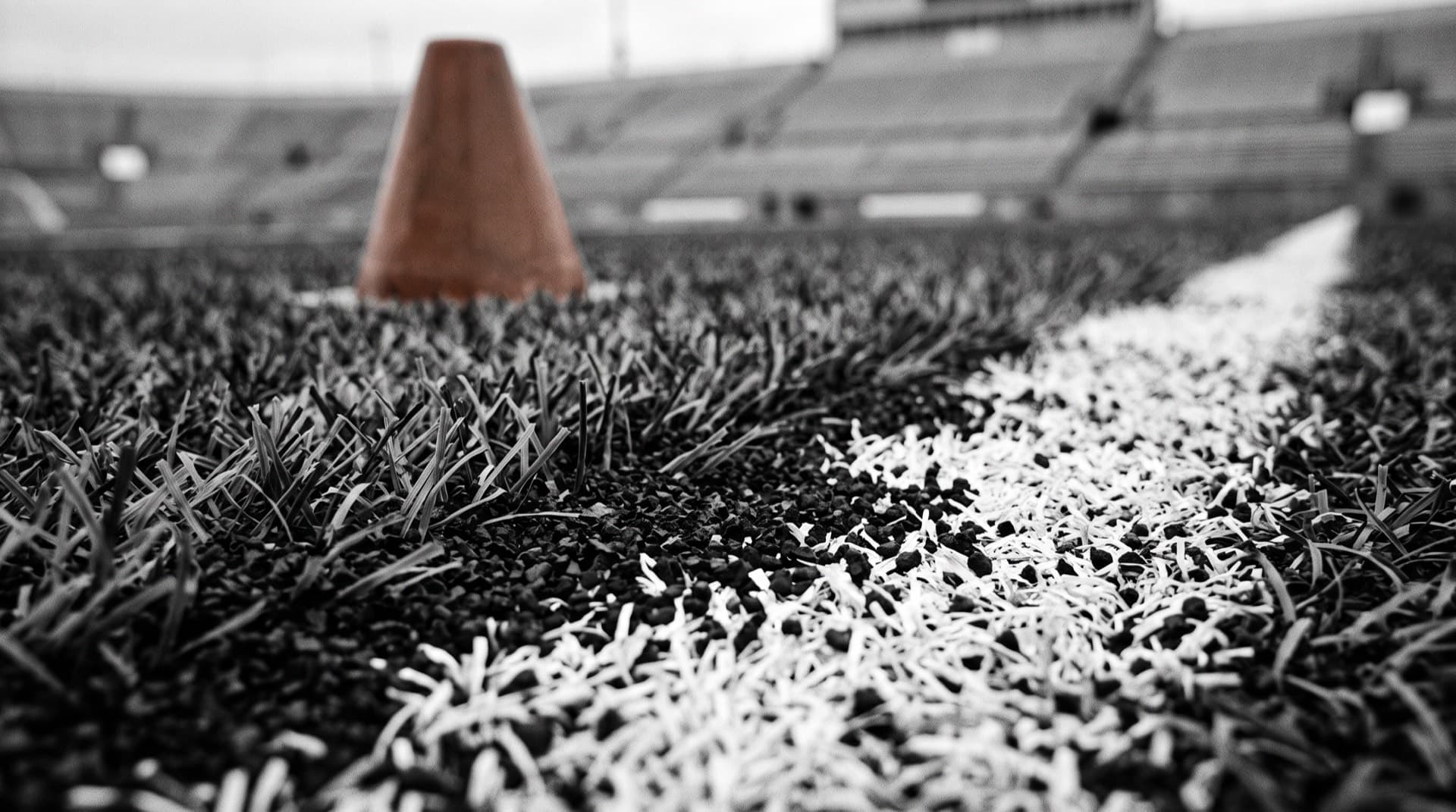 Artificial turf fibers and crumb-rubber infill on a field sideline (photo illustration)