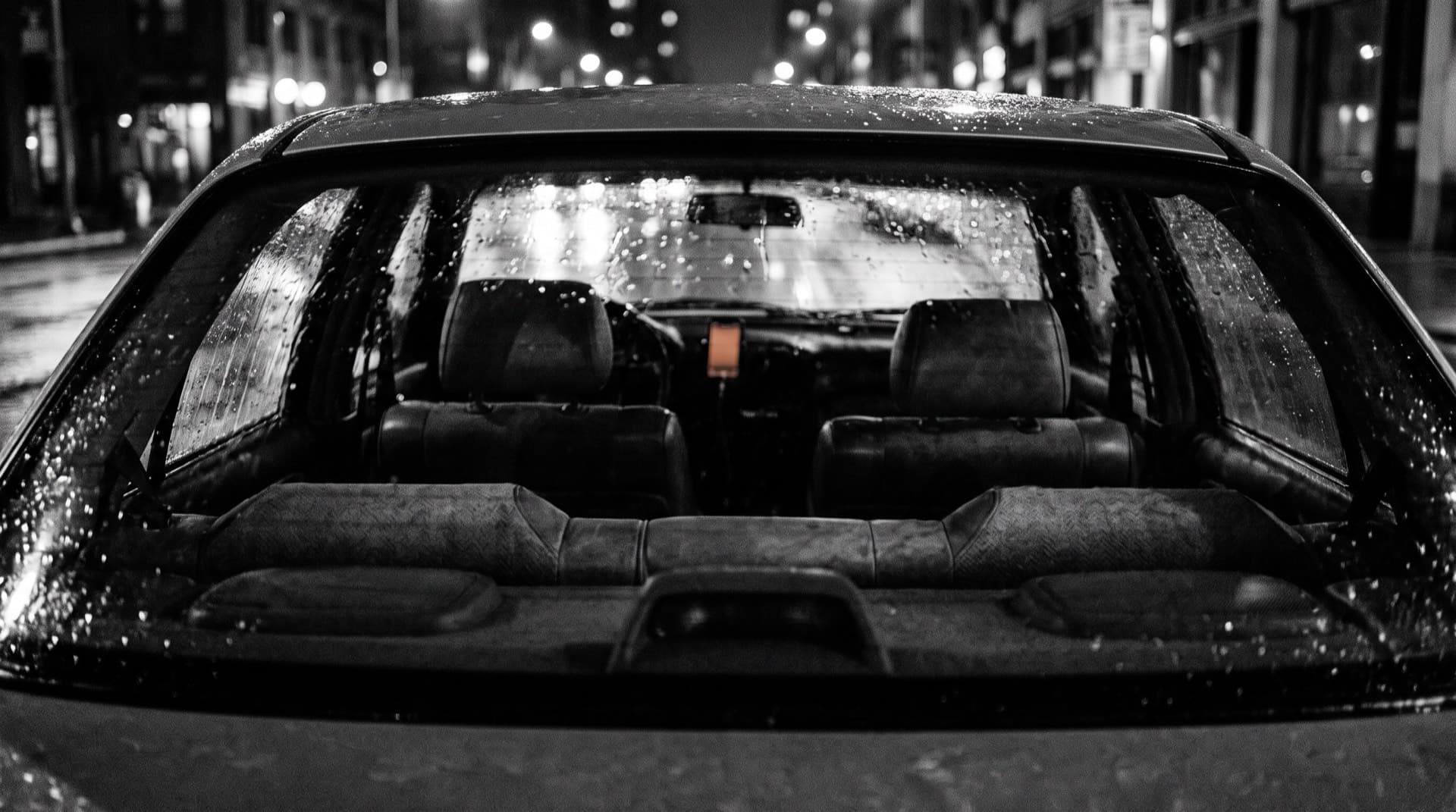 A car back seat through a rain-streaked window at night (photo illustration)