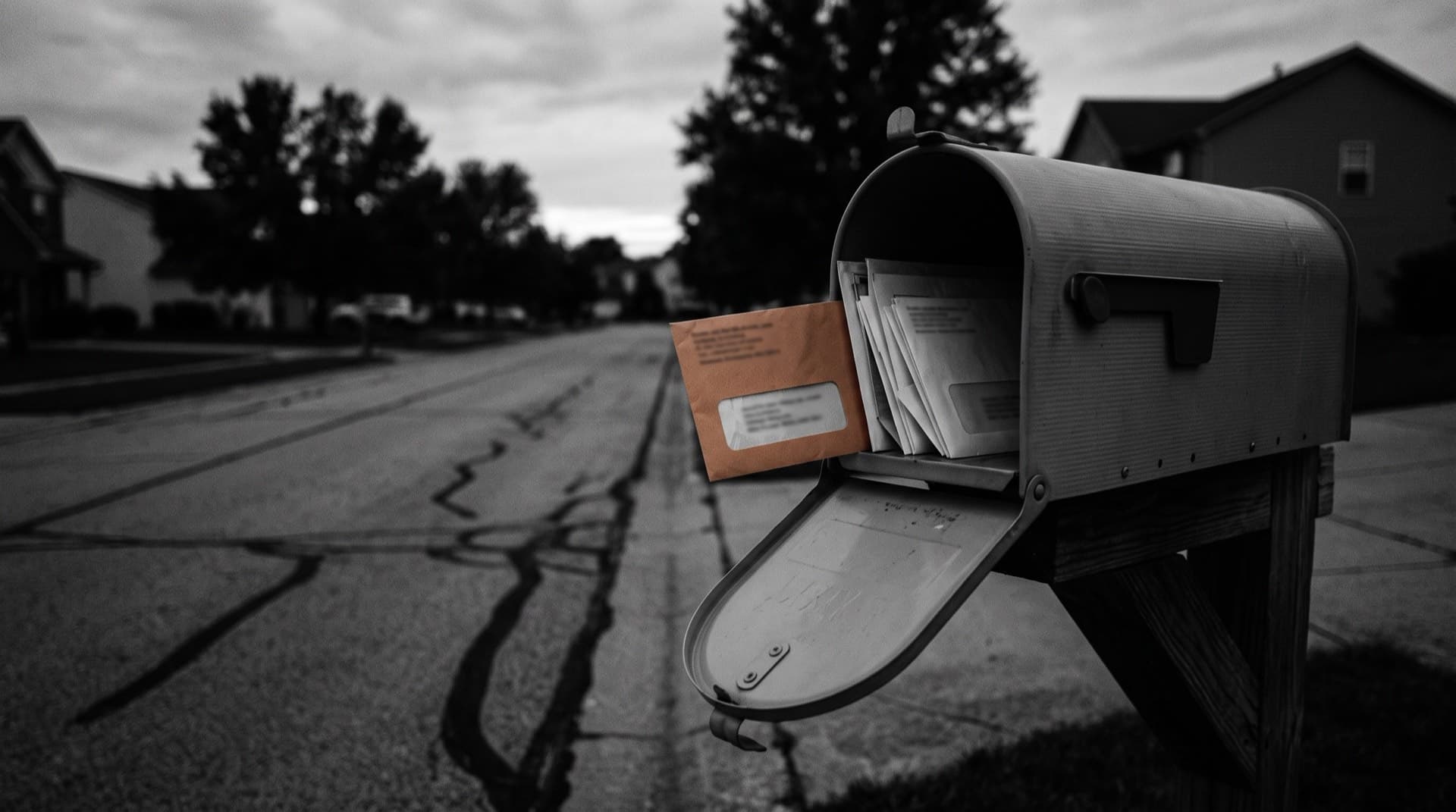 A mailbox stuffed with envelopes, one pulled halfway out (photo illustration)