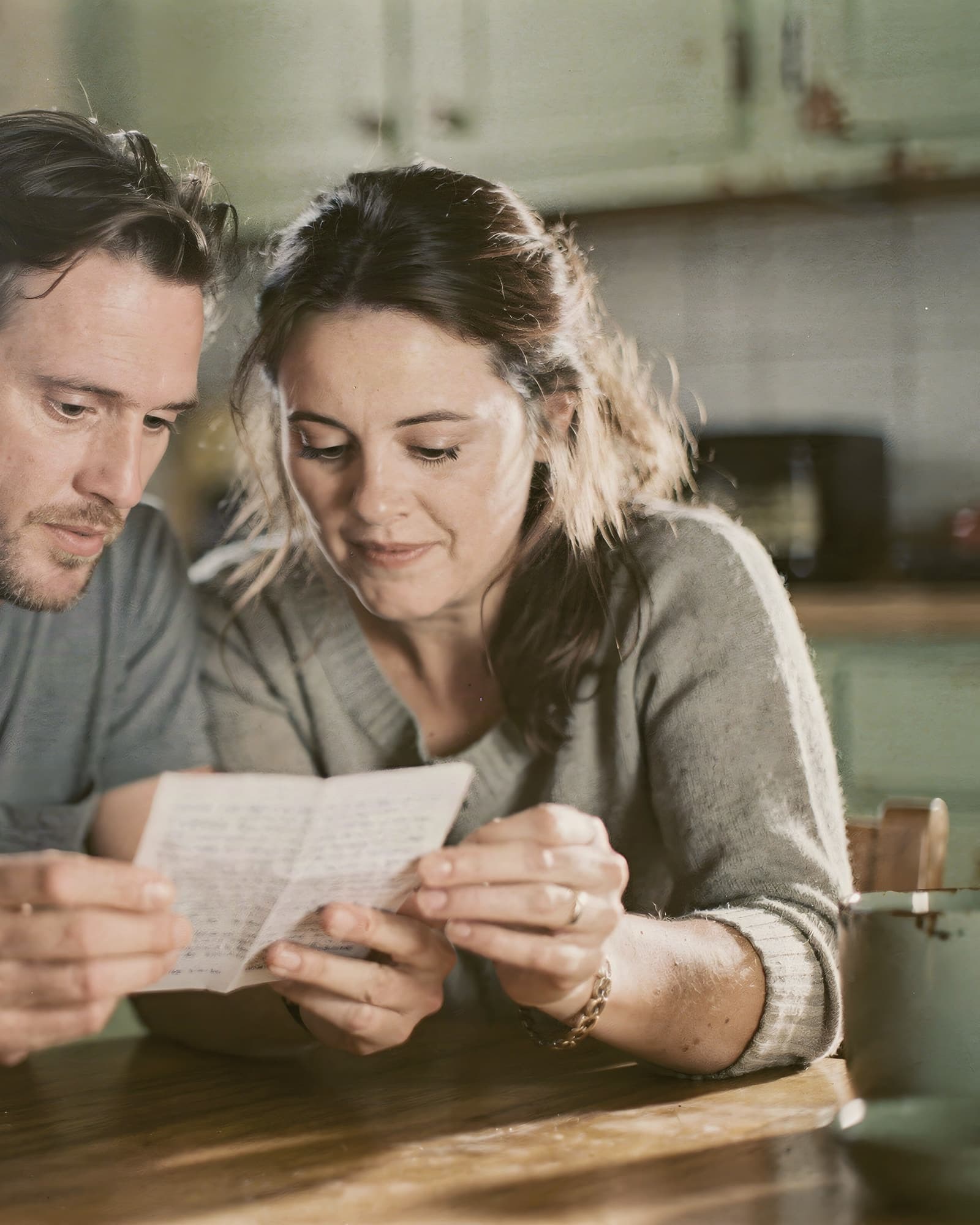 Couple reading a settlement letter together at the kitchen table