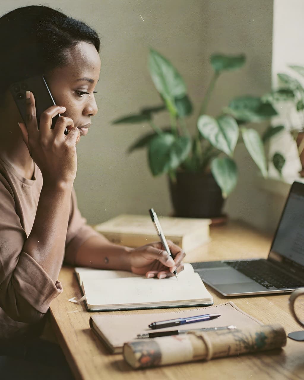 woman on the phone at her laptop checking dates in her notes
