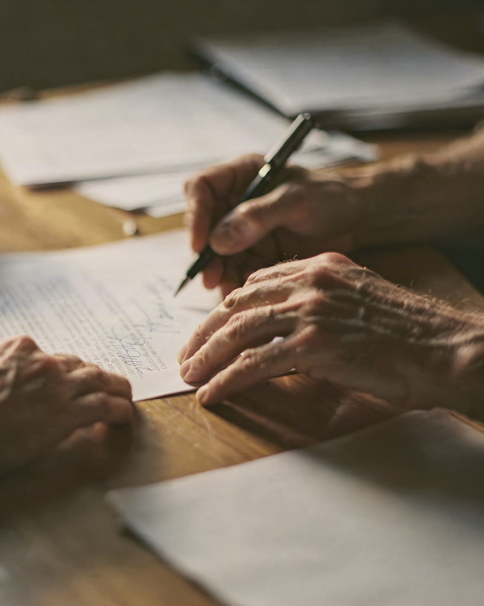 hands signing papers on a desk
